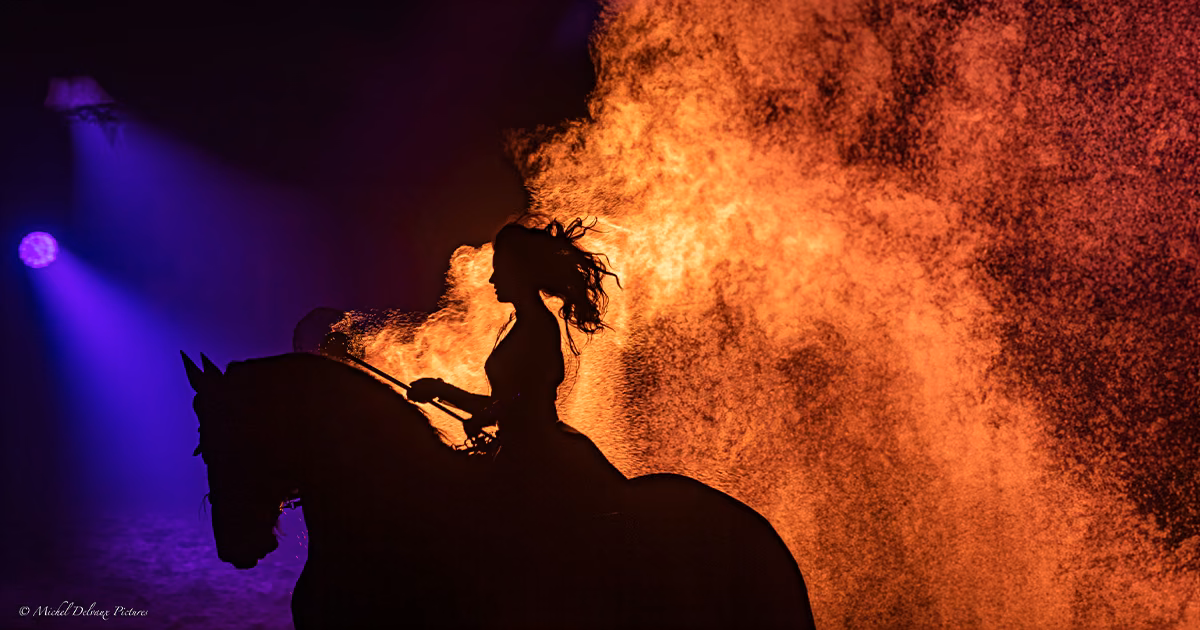 Une cavalière et son cheval se détachent devant une projection de feu.