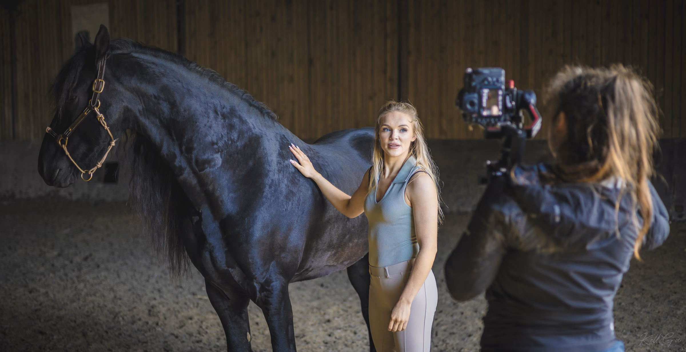 Une prise de vue avec une femme et un cheval noir dans un manège.