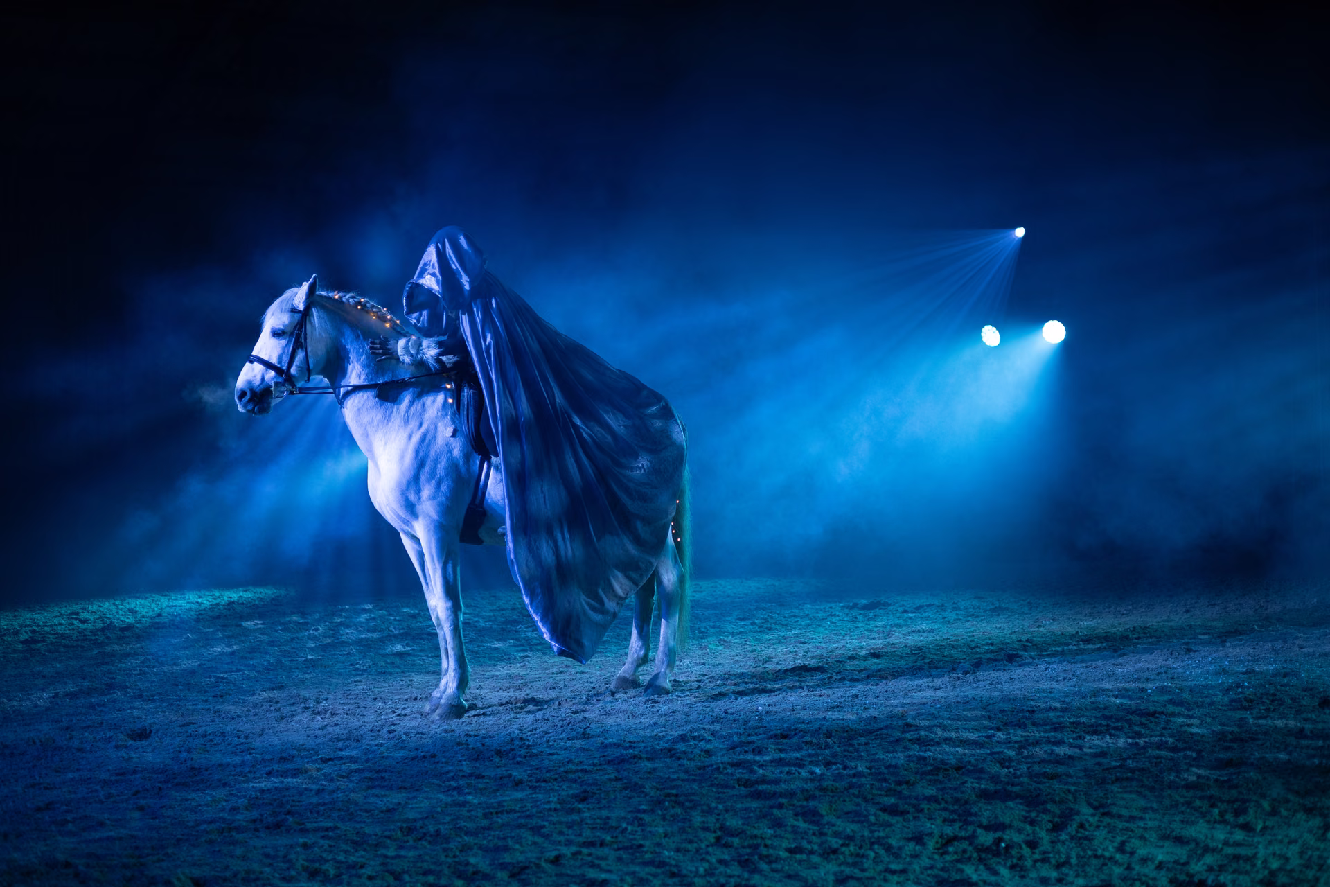 Boréalis : cheval blanc et cavalier encapuchonné dans une brume bleue et turquoise.